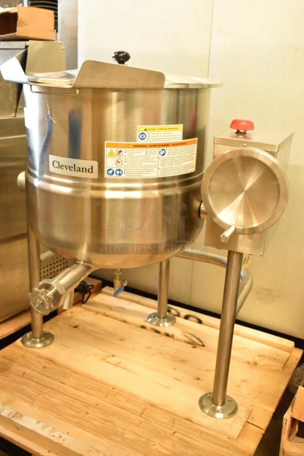 Brand new Cleveland KDL-25-T stainless steel 25-gallon steam kettle with safety labels, slight scratches, on wooden pallet.