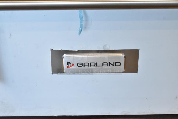 Brand new Garland G36-6 stainless steel commercial range, 6 burners, standard oven, featuring over shelf, backsplash.