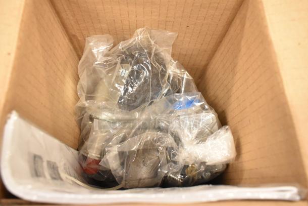 Cardboard box containing parts wrapped in clear plastic, likely new components for the Garland G36-6 commercial range.