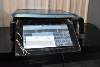 Alt Text: 2024 Hobart HTi metal commercial countertop food portioning scale, touchscreen, new with protective film, 120/208-240V.
