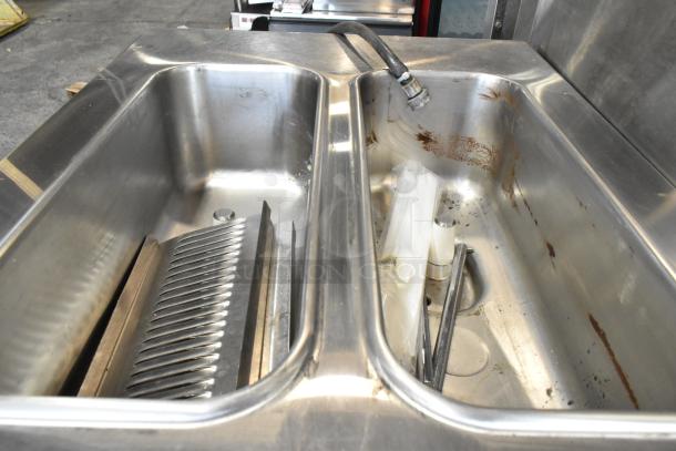 Taylor C723-33 stainless steel soft serve ice cream machine interior, showing dual basins with a drain, signs of use, and fittings.