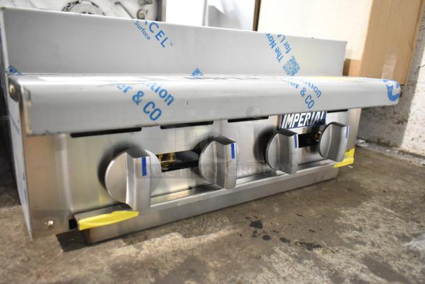 Brand new Imperial IRB-24 stainless steel 24" liquid propane charbroiler, visible control knobs, wrapped in protective film.