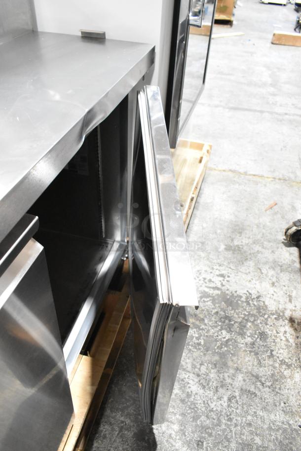 Brand new 2025 Avantco 178SSPPT3 stainless steel commercial pizza prep table with scratches and dents, door ajar, on casters.