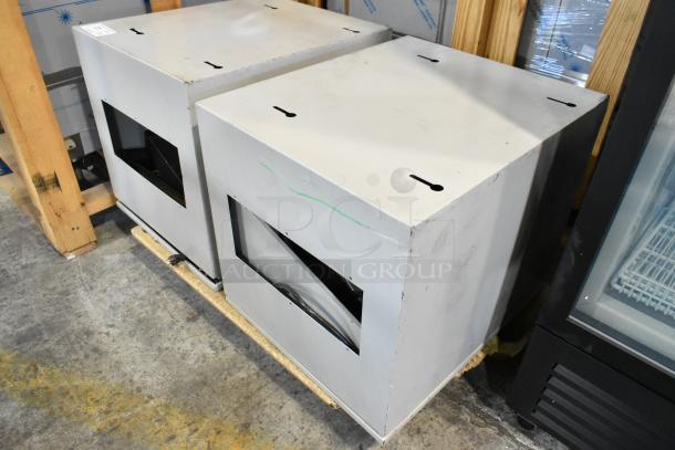 Two gray rectangular metal boxes with open fronts, showing light wear, placed on wooden pallets.