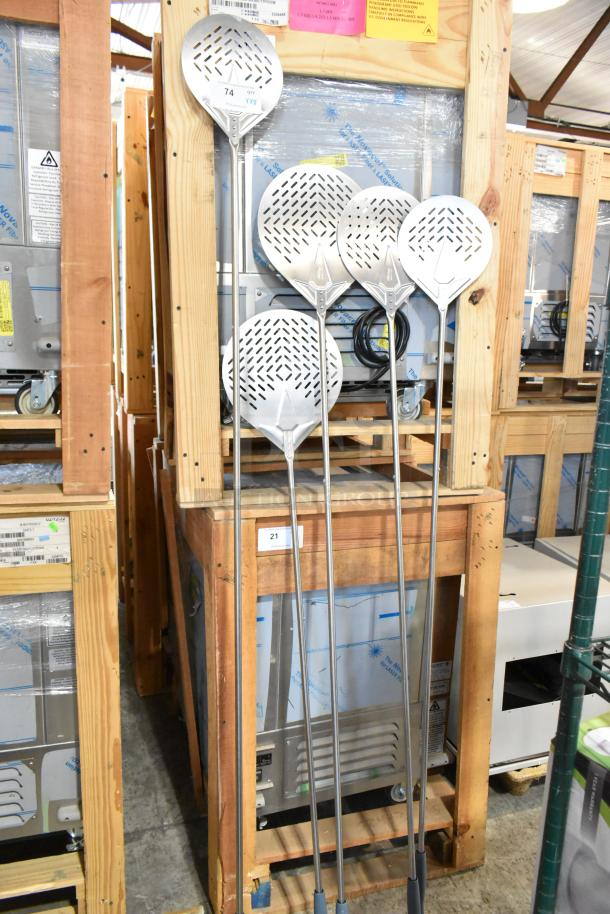 Nine new scratch and dent pizza peels, various sizes, metal construction, perforated design, lean against a pallet.