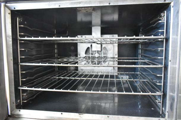 Stainless steel commercial convection oven with view-through door, metal racks, and thermostatic controls. In good condition.