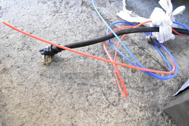 Power cords and cables on a concrete floor, likely for connecting a commercial appliance.