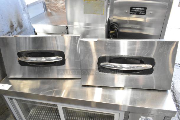 Two stainless steel cooler drawers, featuring sturdy handles, showing signs of wear; ideal for refrigeration units.