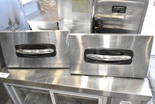 Two stainless steel cooler drawers, featuring sturdy handles, showing signs of wear; ideal for refrigeration units.