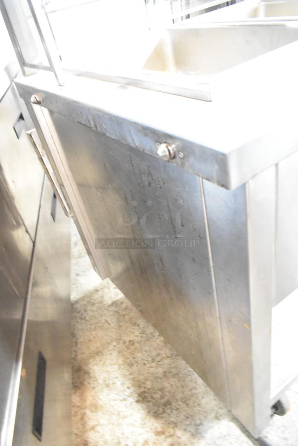 APW Wyott TM-90D stainless steel commercial steam table with tray slide, sneeze guard, and under shelf on casters.