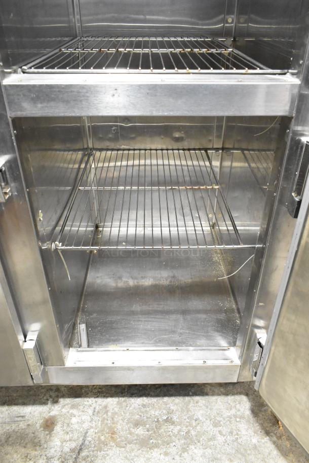 Traulsen RDT332NUT-HHS stainless steel commercial refrigerator/freezer interior with metal racks, visible wear, on casters.