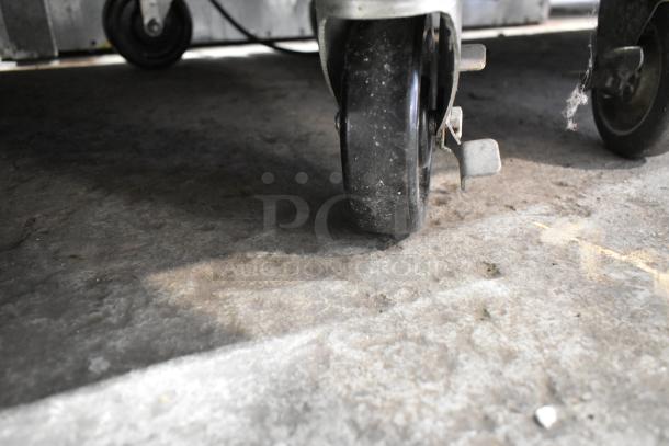 Close-up view of a commercial caster wheel on a Traulsen RDT332NUT-HHS refrigerator/freezer, showing some wear and dirt.