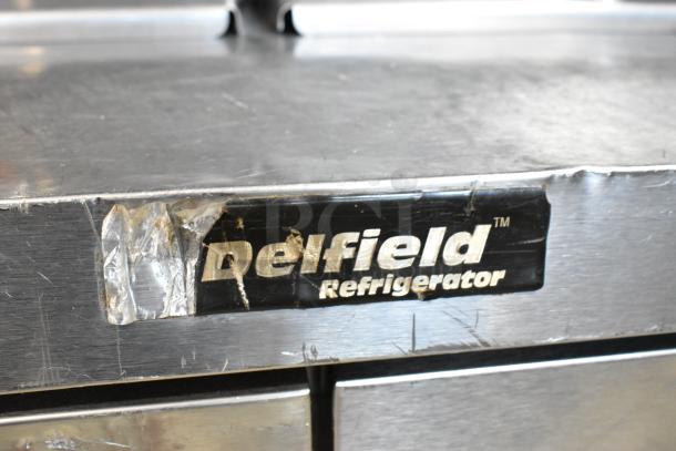 Delfield DD4464N-12-DD4 stainless steel prep table with visible brand label, indicating wear.