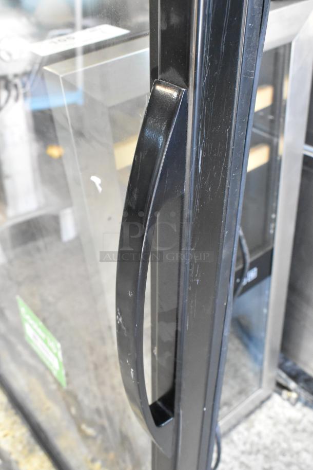 Glass door for merchandiser with black metal handle, slight scuffs visible, used condition.
