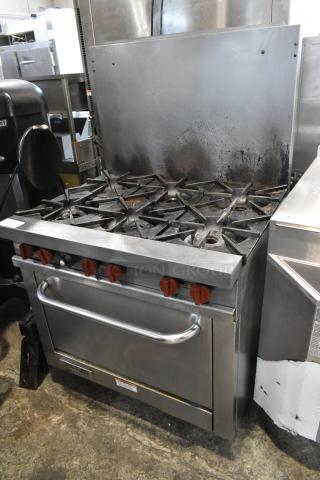 Vulcan stainless steel commercial gas 6-burner range with oven and backsplash, used, visible wear, red knobs.