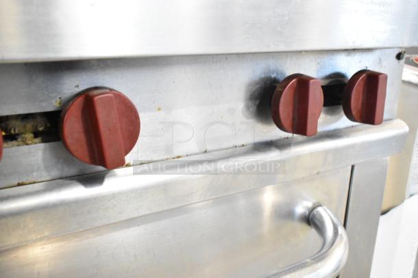 Vulcan stainless steel commercial gas range with six burners, oven, and backsplash. Features red control knobs.