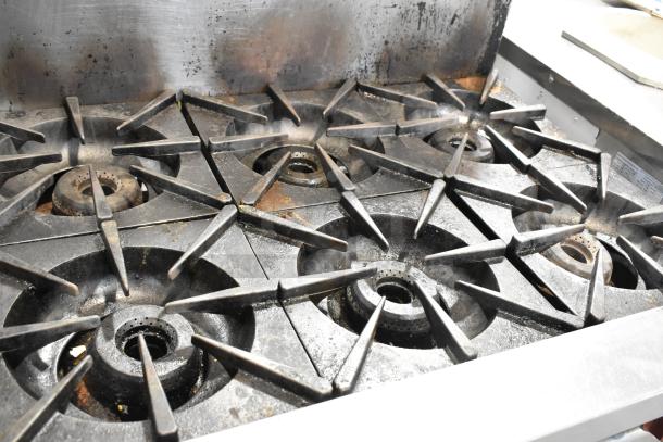 Vulcan stainless steel commercial gas range, 6 burners, with oven and backsplash. Used condition, visible wear.