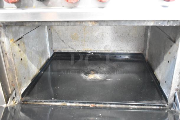 Vulcan stainless steel commercial gas 6-burner range with oven, visible wear inside, suitable for heavy-duty kitchen use.