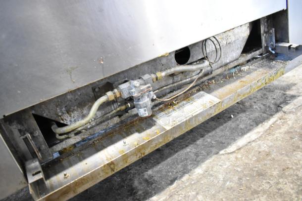 Vulcan stainless steel commercial gas range underside, showing pipes and labels. Condition shows wear and dirt. 6 burner range.