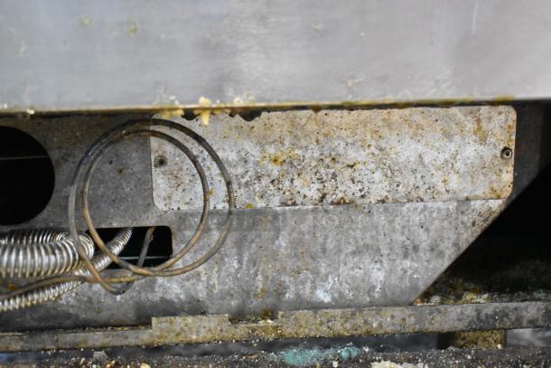 Vulcan stainless steel commercial gas 6-burner range with oven and backsplash, showing wear and residue.