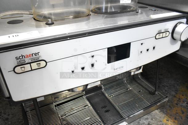 2018 Schaerer Barista Stainless Steel 2 Group Espresso Machine. Features dual latte/cappuccino steam options. Slight wear visible.