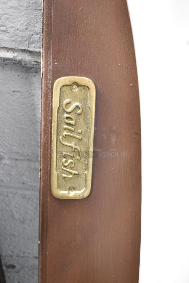 Plaque labeled "Sailfish" on a wooden base, part of decorative fish display.