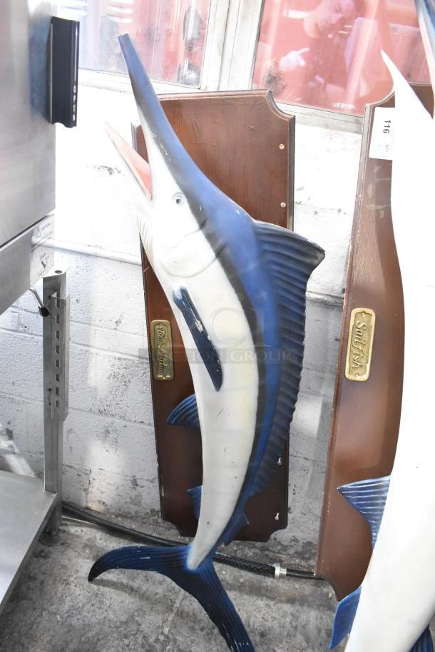 2 decorative fish plaques, featuring Blue Marlin and Sailfish. Plaques mounted on wood with brass labels indicating species.