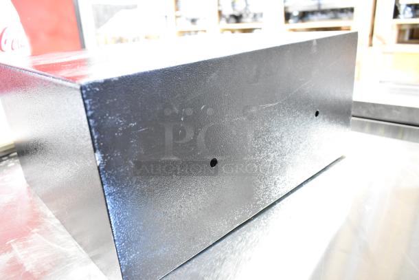 Black metal safe, rectangular, no combination included, visible surface scratches, two small circular holes.