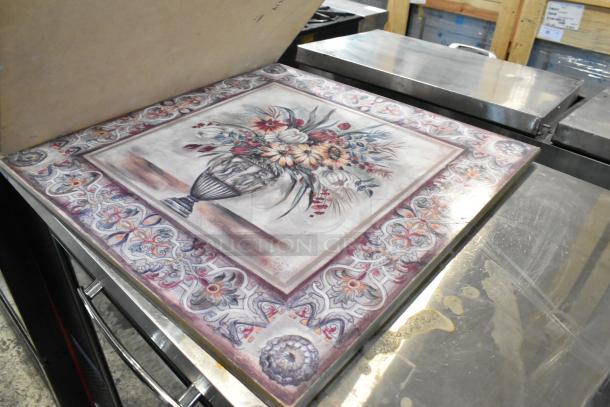 Decorative ceramic tile with floral vase design and ornate border, displayed on metallic surface, with vibrant colors.