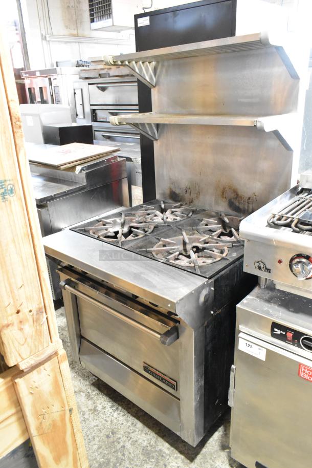 Garland M44R stainless steel 4 burner range with oven, backsplash, and 2-tier over-shelf. Natural gas powered, commercial use.