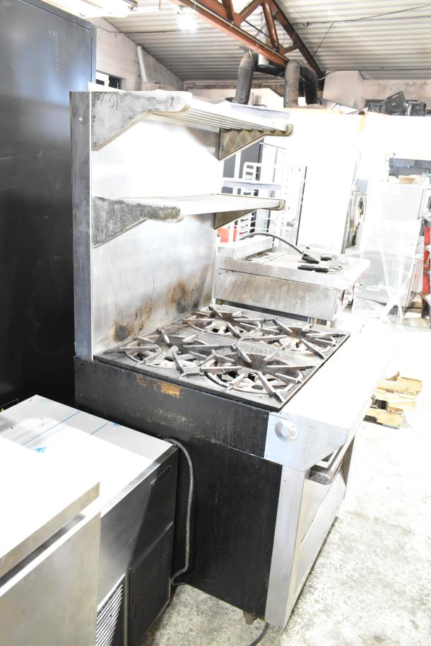 Garland M44R stainless steel gas 4 burner range with oven, backsplash, 2-tier shelf; commercial grade. Signs of use visible.