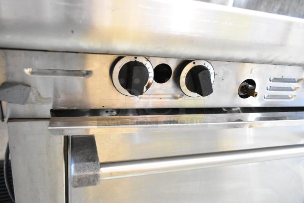 Garland M44R stainless steel commercial range with 4 burners, oven, backsplash, and 2-tier over-shelf. Natural gas-powered.