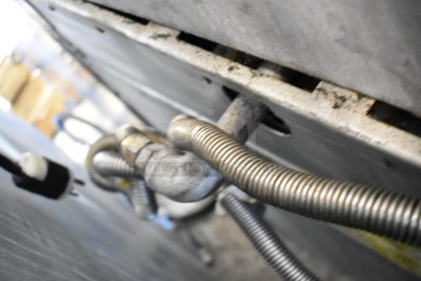 Garland M44R stainless steel commercial gas range connections, showing coiled tubing and plug, emphasizing durability.