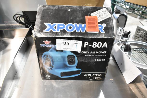 Brand new Xpower P-80A Air Mover in box, 600 CFM, 3-speed, with power outlets, model details and branding visible on packaging.
