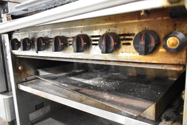 MagiKitch'n 636 stainless steel commercial charbroiler grill, 6 dials, under shelf, on casters, showing some wear.