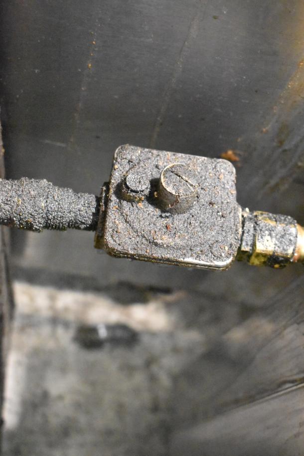 MagiKitch'n 636 stainless steel natural gas charbroiler grill, focus on gas valve detail, showing wear and residue buildup.