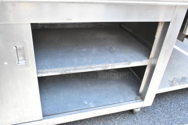 "Stainless steel table with under shelves, drawers, and doors. Durable, spacious, perfect for storage. Good condition."