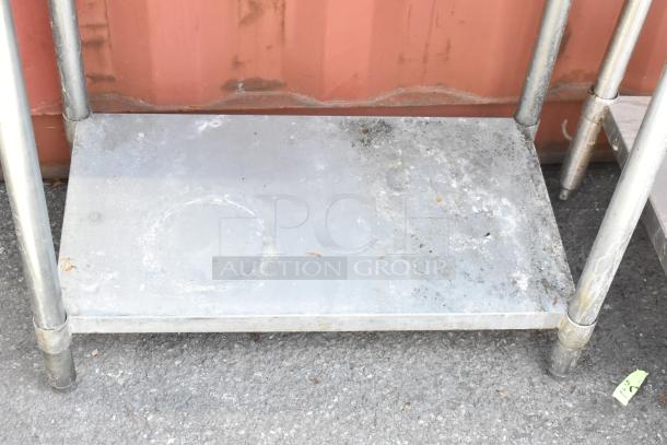 Stainless steel table with a metal under shelf, showing wear. Ideal for industrial use; sturdy and functional.
