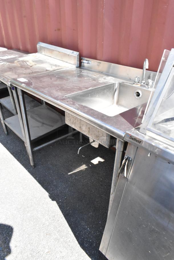 Stainless steel table with sink basin, faucet, and handles. Features Delfield branding. Good condition, suitable for kitchens.