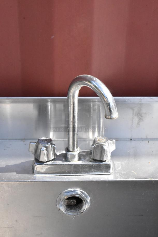 Stainless steel table with sink basin and chrome faucet. Features hot and cold handles. Used condition, visible wear.