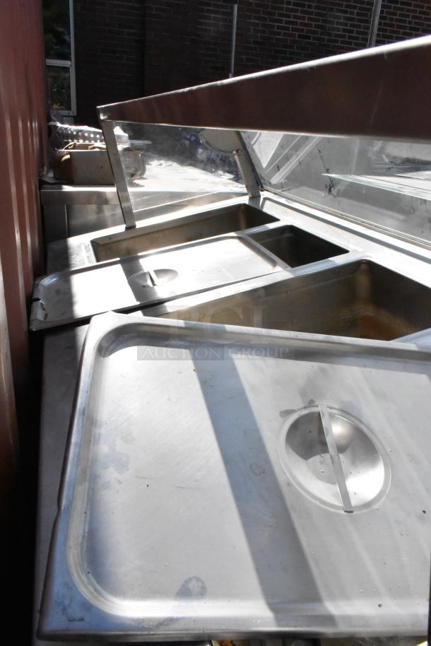 Delfield stainless steel 4-bay steam table with sneeze guard, used condition, visible wear, ideal for commercial use.