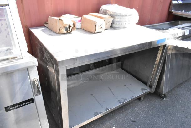 Stainless steel table with metal under shelf, includes various boxed contents; shows signs of wear, suitable for kitchen use.