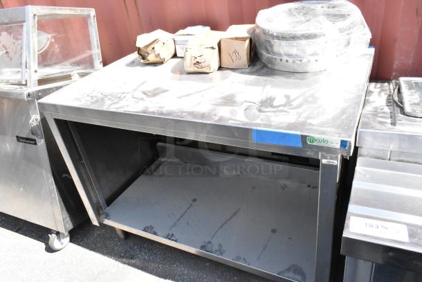 Stainless steel table with metal under shelf. Includes various boxed contents. Marlo Mfg Co label visible. Used condition.