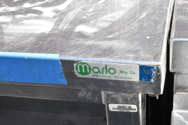Stainless steel table by Marlo Mfg. Co. with metal under shelf. Visible wear on surface, features manufacturer's label.