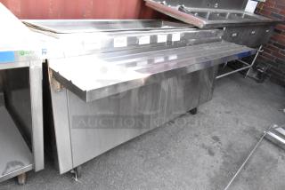 Stainless steel prep table with tray slide and commercial casters, featuring visible surface wear and "Marlo" label.