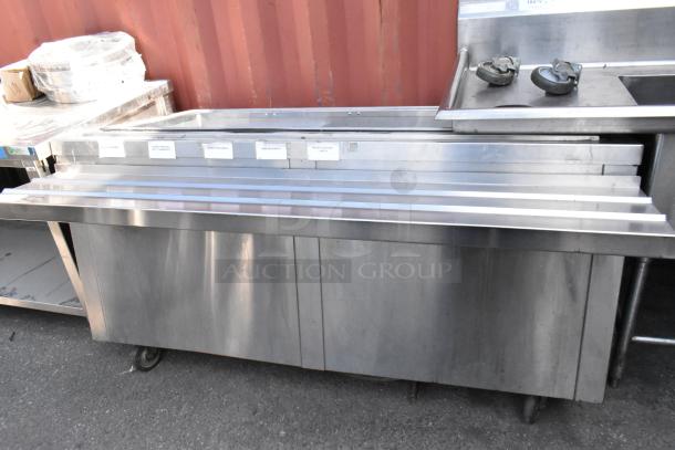 Stainless steel prep table with tray slide, commercial casters; good condition; labeled sections for easy food prep.