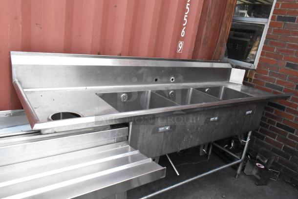 Stainless steel 3 bay sink with left side drain board. Features three compartments, clean surface, ideal for commercial use.