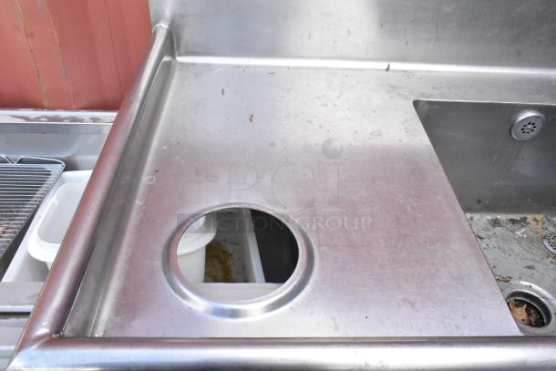 Stainless steel 3 bay sink with left side drain board, shows signs of wear. Visible detail includes an integrated waste hole.