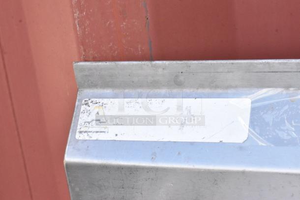Stainless steel 3 bay sink with left side drain board, showing minor wear. Manufacturer label partially visible.