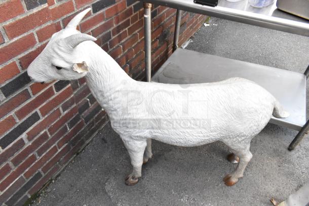 White goat statue with realistic texture, standing near a brick wall. Good condition, minor wear on ear.